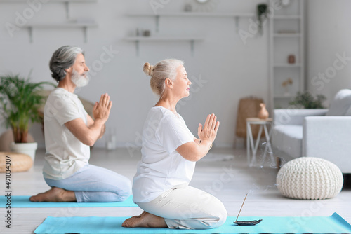 Mature couple practicing yoga at home
