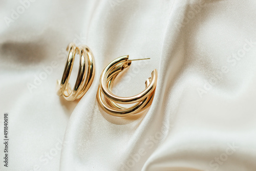 Gold jewelry earrings made of gold on the background of silk.