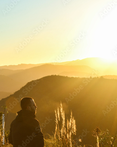homem contemplando o nascer do sol com montanhas ao fundo 