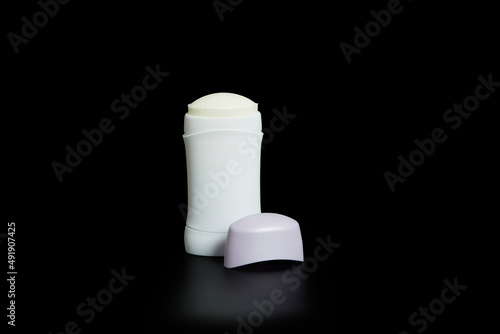 Non-branded deodorant stick. Transparent white bottle with lid set on black background and with reflection.