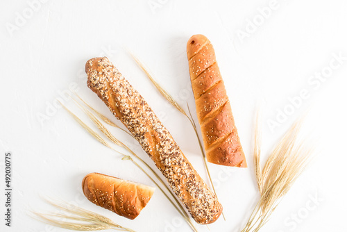 two types of baguette with different seeds on a white background with ears of wheat. top view. flat layout.