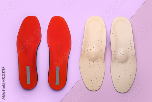 Two pairs of orthopedic insoles on lilac background