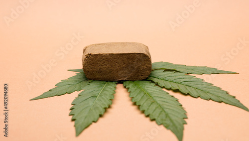 portion hashish tablet with marijuana leaf, bronw background