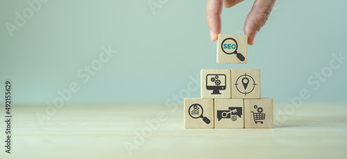 SEO, Search Engine Optimization ranking concept. Digital marketing strategy of promote traffic to website. Hand holds wooden cubes with the icon of magnifying glass with alphabets abbreviation SEO.