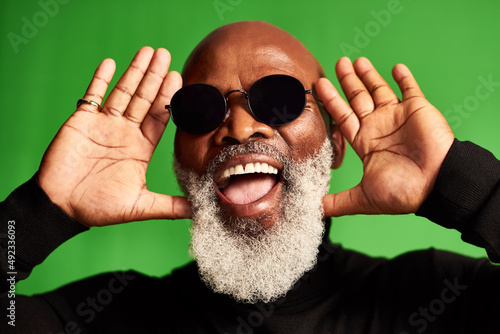 Growing old doesnt mean you have to be boring. Studio shot of a senior man wearing glasses and making funny faces against a green background.