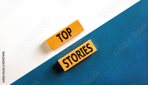 Top stories symbol. Concept words Top stories on wooden blocks on a beautiful blue table white background. Business story and top stories concept, copy space.
