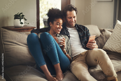 Lock the door, leave the world outside. Shot of a happy young couple using a digital tablet while relaxing on a couch in their living room at home.