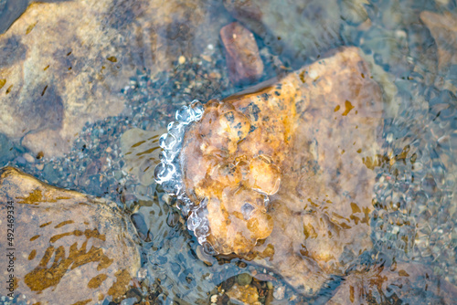 Water surface with rocks bottom in flowing stream, textured nature background photography