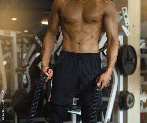 Body of Young man with fit and firm muscle,holding black rope in hand .prepare for doing exercise,