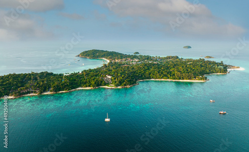 bove view of the Tropical island beach with seashore as the tropical island in a coral reef ,blue and turquoise sea with local boat background