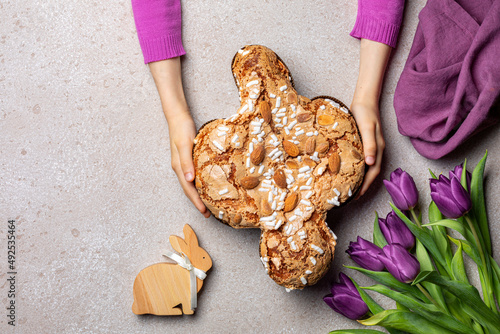 Easter tradition in Italy, Dove Cake topped with icing and almonds. Colomba di Pasqua. Easter bunny. Spring violet flowers. Top view.