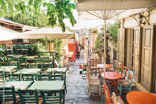 Athens, Greece, beautiful street in old district of Plaka. Colorful view of greek street with cafe tables and flowers. Famous tourist destination and travel attraction in Europe.