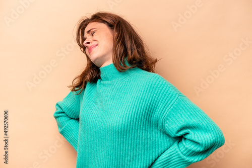 Young caucasian woman isolated on beige background suffering a back pain.