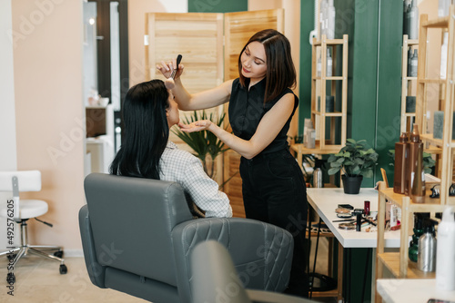 The makeup artist girl applies powder or blush to her client, completes the image. Beauty, makeup, style