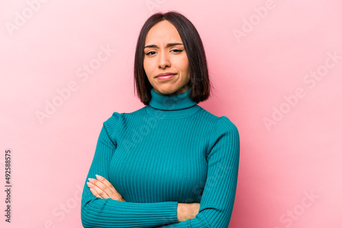 Young hispanic woman isolated on pink background unhappy looking in camera with sarcastic expression.