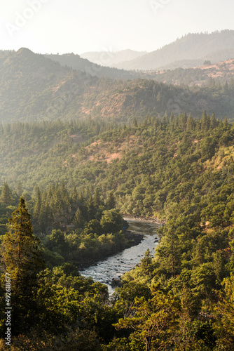 A river flows through forested hills at sunset