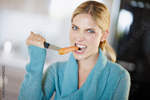 Dieting isnt for sissies. Portrait of a beautiful young woman aggressively taking a bite out of a carrot.