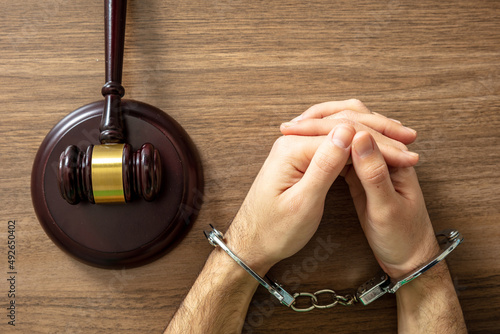 Handcuffed Convict. Court sentence Prison. Handcuff locked and judge gavel on table, top view..