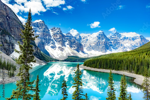 Famous Moraine lake in Banff National Park, Canadian Rockies, Canada. Sunny summer day with amazing blue sky. Majestic mountains in the background. Clear turquoise blue water.