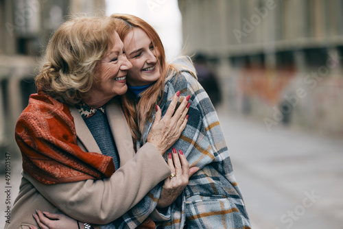 A happy grandmother and granddaughter hugs outside.