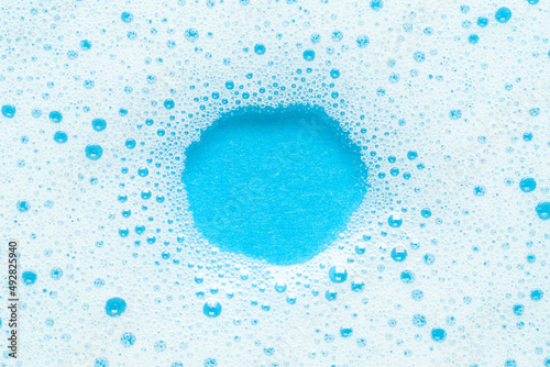 Foam and bubbles on a blue background. Empty space for advertising, round mock up for text.