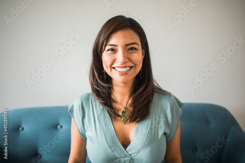 portrait of a smiling latin woman looking at the camera sitting on the sofa at home