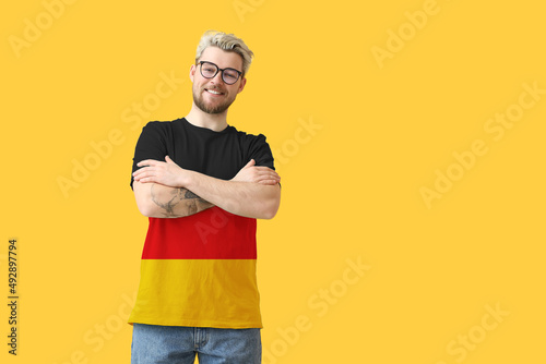Young man wearing t-shirt in colors of German flag on yellow background