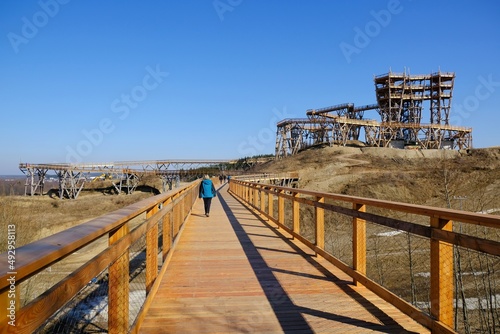 Wooden footbridge with walking person. Lookout tower at Kurza Gora in background. Kurzetnik, Warmia and Masuria, Poland