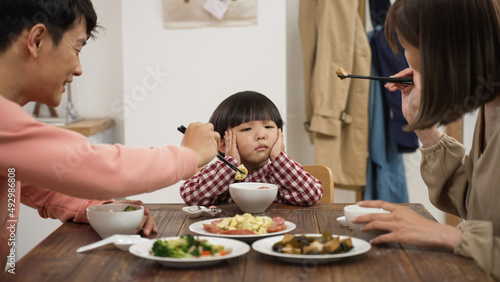 closeup of unhappy Asian preschool boy shaking head and saying no to eat at dining table to his mom and dad at home