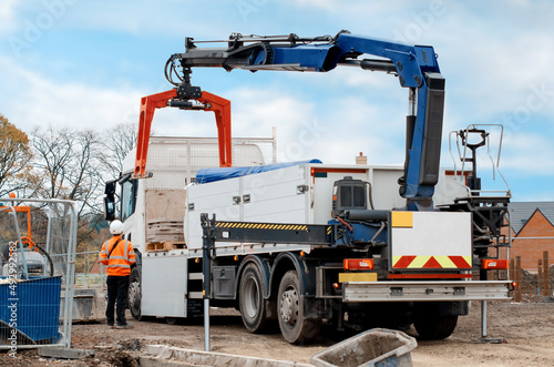 Dropside flatbed HIAB crane lorry with brick grab attachment deliver materials on construction site and offloading them