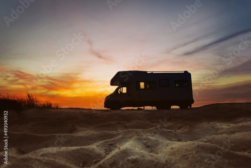 Sunset and caravan silhouette. Van life concept. Travelling in the Europe. Camper van on the beach.