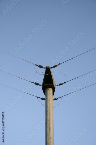 Torre de baja tensiòn en àngulo con sus conexiones de cables elèctricos sobre cremalleras para distribuciòn de luz en barrios, forma un diseño industrial con fondo de cielo azul