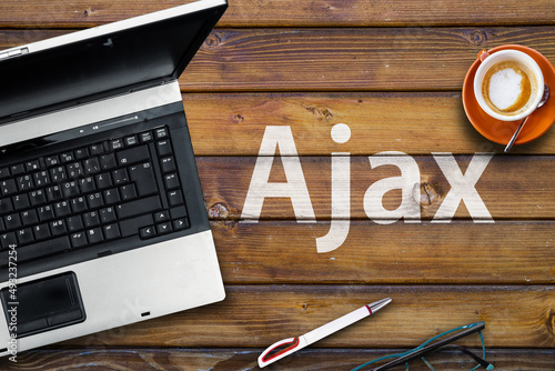 Ajax programming language. Word Ajaxand laptop, glasses and coffee on wooden table 