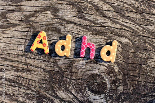 Letters ADHD written on colorful toy text on wooden surface. Attention deficit hyperactivity disorder concept.