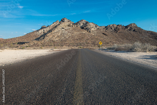 Road and mountains in the Baja, near the sea of cortes in the state of Baja California Sur, in Mexico. horizontal landscape with blue sky in a hot summer afternoon travel and destination concepts.