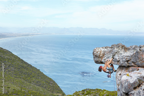 Taking thrill-seeking to new heights. A young woman climbing up the side of a mountain.