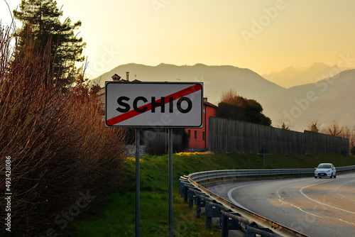 End of the holidays concept - Inscription "Schio" (town and comune in the province of Vicenza) on a traffic sign indicating the end of the town. On the background the Little Dolomites are visible