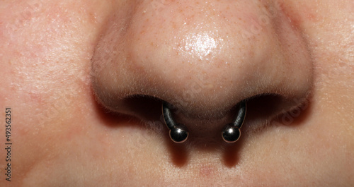 Girl's nose piercing. Septum piercing. Macro. Titanium piercing jewelry with balls.