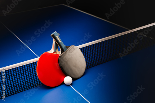 Ping pong rackets and balls on a blue table with net.