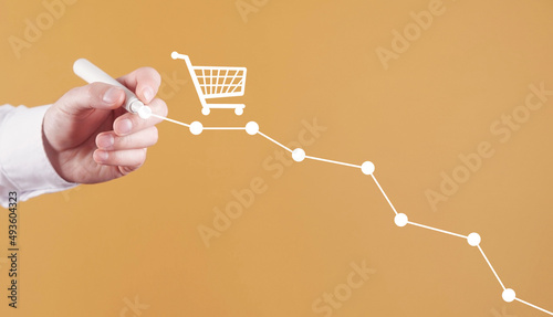 Male hand draws down graph with a shopping cart. Sales decline