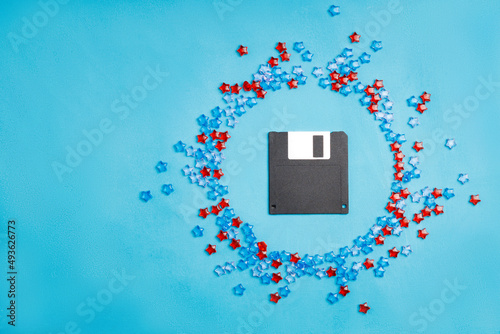 a black floppy disk on a blue background, plastic stars are located around
