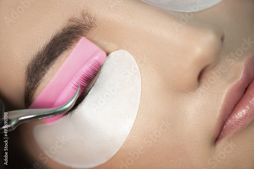 Master glues eyelashes to pink lash roller. Close-up of beauty model's face during lash lift laminating botox procedure. Eyelash Care Treatment: eyelash lifting and curling, lash lamination 