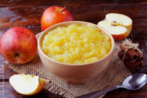 homemade apple sauce or apple puree in ceramic bowl over rustic wooden table. top view