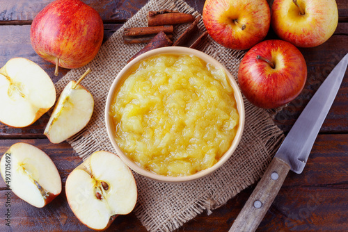 homemade apple sauce or apple puree in ceramic bowl over rustic wooden table. top view