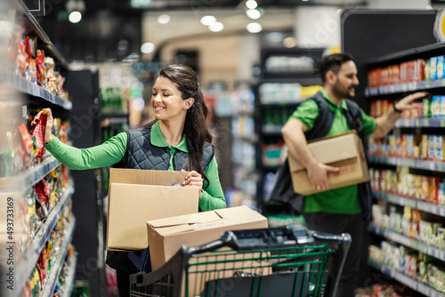 The employees arranging groceries on shelves in supermarket.