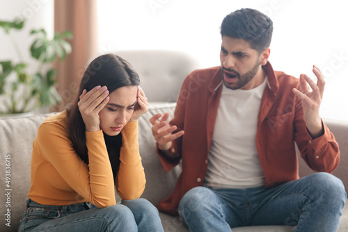 Angry Muslim Husband Yelling Wife Sitting On Sofa At Home