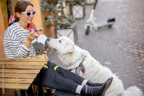 Woman cares her dog while eating pasta at outdoors cafe in Rome city. Concept of italian lifestyle, gastronomy and travel. Idea of friendship with a dog