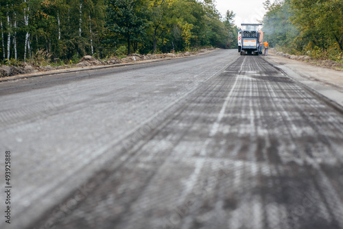 Road milling machine removes asphalt from old road and loads milled asphalt in dump truck. 