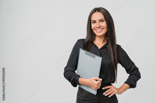 Female young businesswoman auditor inspector examiner controller in formal wear writing on clipboard, checking the quality of goods and service looking at camera isolated in white background