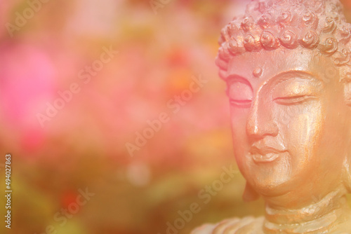Buddha Statue in garden with blurred flowers background